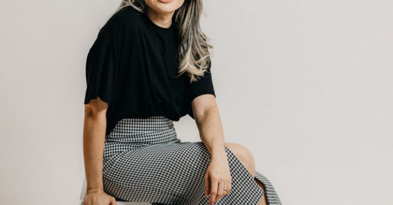 Business Expansion - A woman sitting on a white box with her legs crossed