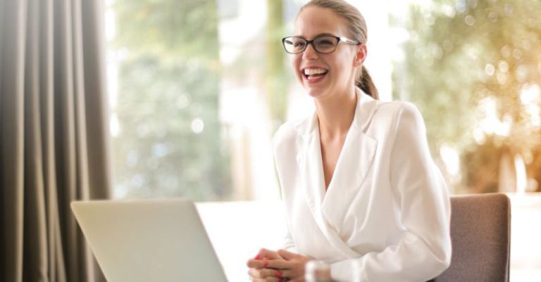 Young Entrepreneur - Laughing businesswoman working in office with laptop